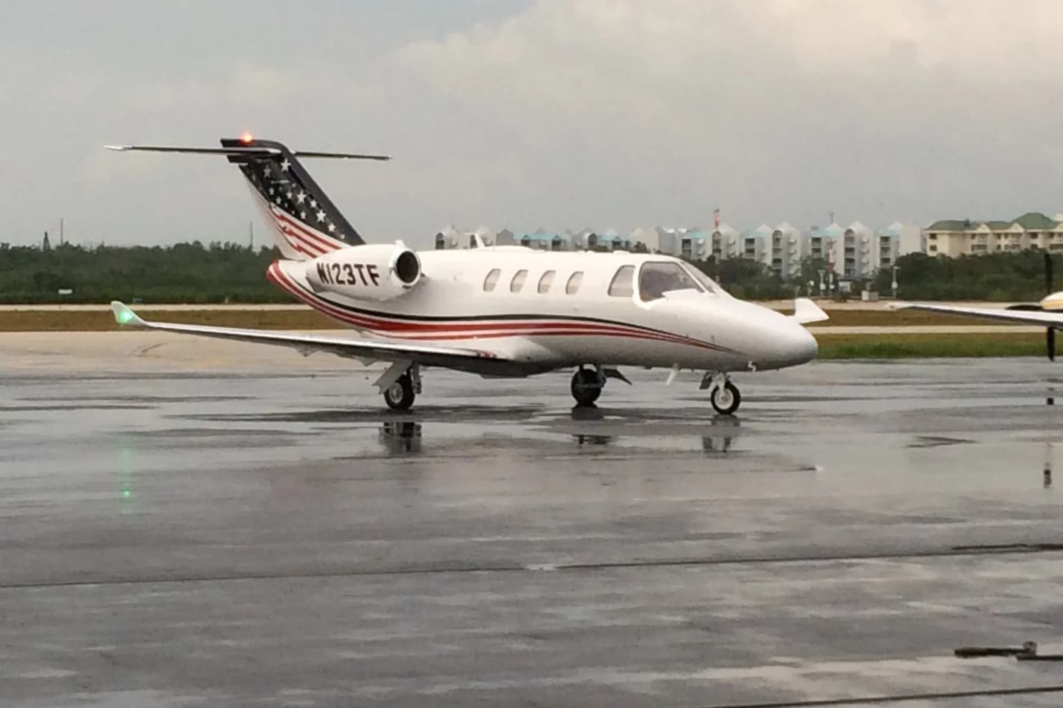 Cessna Citation M2 business jet parked on a wet airport apron.