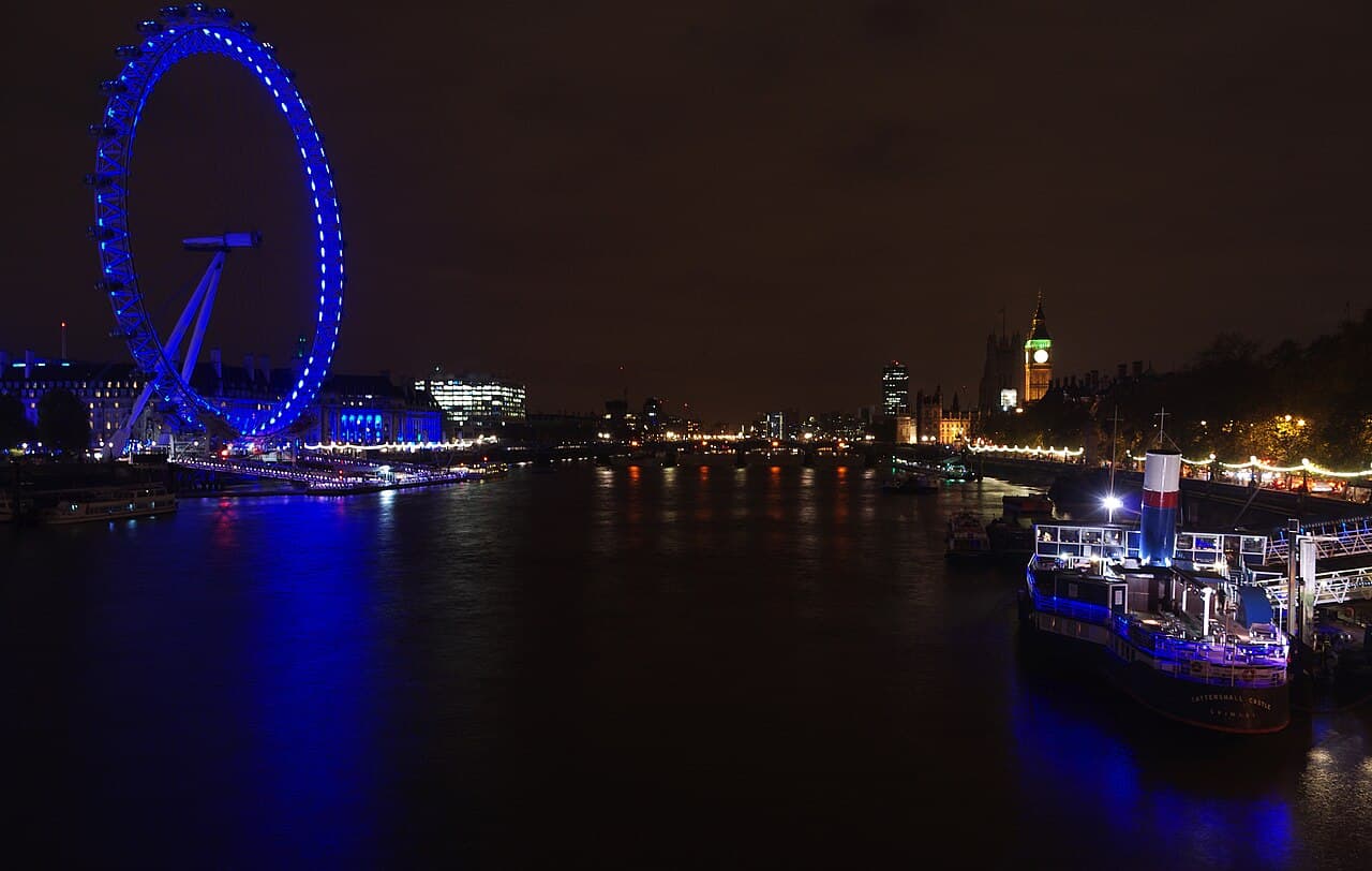 The London Eye and illuminated Thames at night.